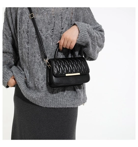 Detalle de bolso bandolera negro acolchado con cierre dorado y texturas