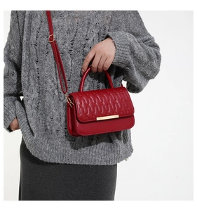 Macro shot of red quilted crossbody bag with luxury gold buckle and fine leather texture
