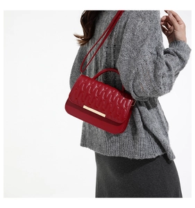Rear view of a model wearing a red quilted crossbody bag with golden metal buckle