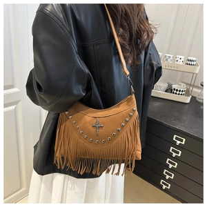Close-up of bohemian brown suede shoulder bag with vintage rivets and long tassels