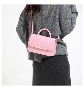 Detailed side view of pink quilted handbag with gold trim on gray knit sweater