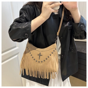 Détail du sac bandoulière vintage en daim avec longues franges, rivets et pendentif croix