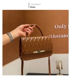 Dettaglio borsa marrone in ecopelle trapuntata con cuciture ondulate e barra in metallo oro