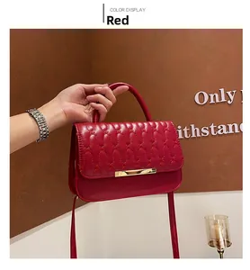 Dettaglio borsa trapuntata rossa in ecopelle con elegante chiusura a barra in metallo oro