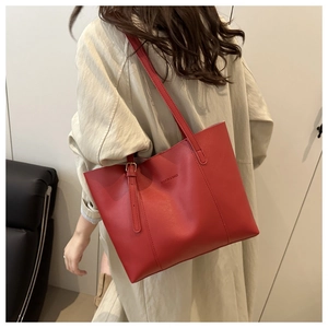 Model wearing a red lychee-pattern tote bag with fashion lettering and gold hardware