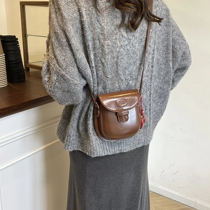 Borsa a sella vintage in pelle marrone da donna indossata da modella in un caffè elegante