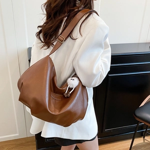 Brown pleated faux leather tote bag with white faux fur charm in a minimalist room