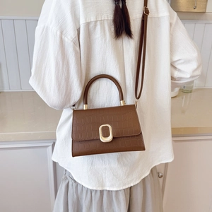 Sac bandoulière marron motif crocodile avec boucle dorée porté par un mannequin