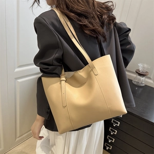 Minimalist beige PU leather tote bag with long straps shown on shoulder for daily commute
