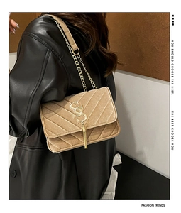 Close-up of brown velvet shoulder bag with V-quilted pattern and gold tassel detail
