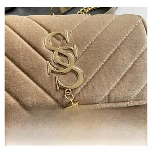 Close-up of beige velvet quilted handbag with gold metal logo and tassel details