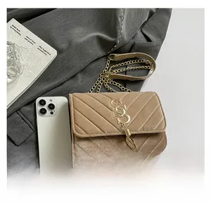 Detail of light brown velvet crossbody bag with gold chain and quilted V-pattern
