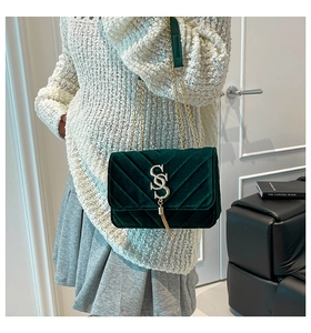 Détail du sac bandoulière en velours vert foncé avec matelassage en V et gland doré