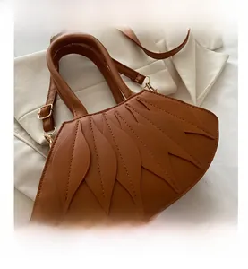 Detailed macro of brown faux leather shoulder bag with unique layered leaf pattern design