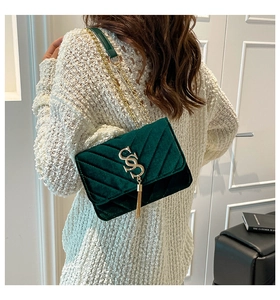 Detail of dark green velvet shoulder bag with V-shaped quilting and gold hardware