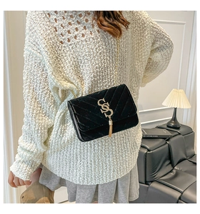 Détail du sac bandoulière en velours noir matelassé avec pompon doré et chaîne