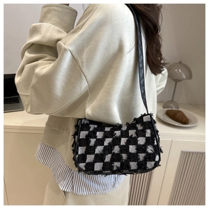 Detail of checkered tweed underarm bag with frayed edges and slim leather shoulder strap