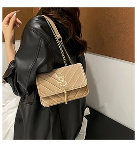 Détail du sac bandoulière en velours beige avec matelassage en V et pompon doré