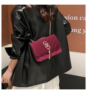 Détail du sac en velours bordeaux avec pompon, chaîne dorée et surpiqûres en V