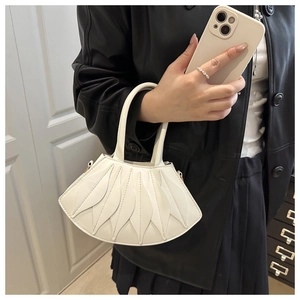 Detail of white handbag featuring unique overlapping leaf pattern and elegant top handle