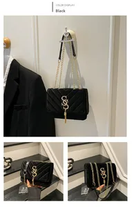 Detail of black quilted shoulder bag with golden double-S buckle and metal tassel