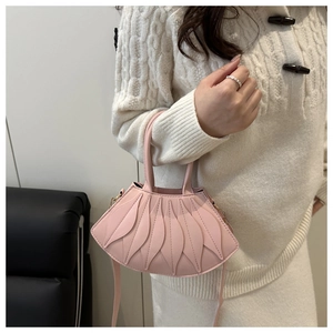 Pink fan-shaped patchwork handbag held by a model wearing an off-white knit sweater