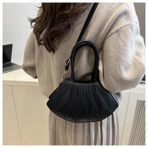 Detail of black fan-shaped handbag with leaf-like stitching and golden metal hardware