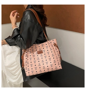 Pink tote bag detail with bear print patterns and brown strap worn by a model