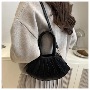 Detail of black semi-circular crossbody bag with leaf-shaped quilted texture and gold hardware