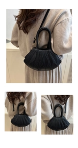 Detail of black shell-shaped handbag with textured leaf patterns and golden hardware