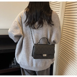 Detail showing classic quilted texture and metal chain strap of the black crossbody bag