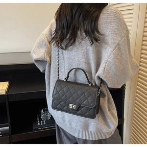Black quilted crossbody bag with silver twist lock and chain strap on a model shoulder