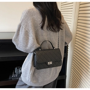 Detail of black quilted leather crossbody bag with silver twist lock and chain strap
