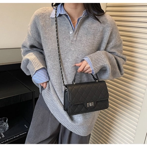 Detail of black quilted leather shoulder bag with silver chain strap and twist lock