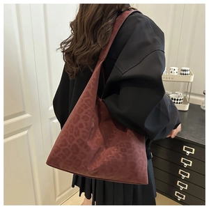 Deep red leopard print tote bag styled with a black outfit in a minimal interior
