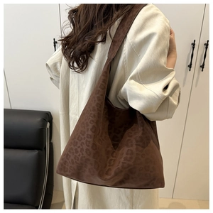Detail of soft leopard print tote bag worn on shoulder for autumn winter fashion look