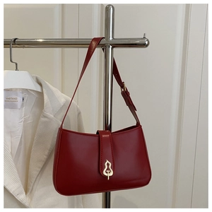 Detailed view of the dark red underarm bag with gold gourd-shaped buckle and fine leather texture