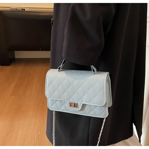 Light blue quilted leather crossbody bag with chain strap shown on model's side