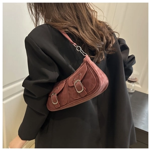 Détail d'un sac demi-lune rétro rouge foncé avec texture suédée et poches à boucles