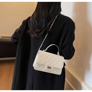 Detailed close-up of quilted pattern leather on white crossbody bag with metal lock