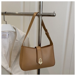 Detail of caramel leather shoulder bag with decorative gold gourd-shaped clasp