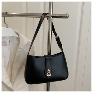 Detail of classic black baguette bag with elegant gold gourd-shaped buckle and strap