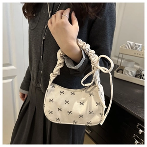 Detail of white corduroy shoulder bag with black bow patterns and drawstring handles