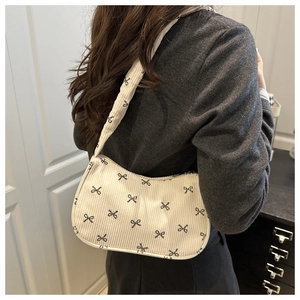 Detail of beige corduroy shoulder bag featuring black bow patterns and soft texture