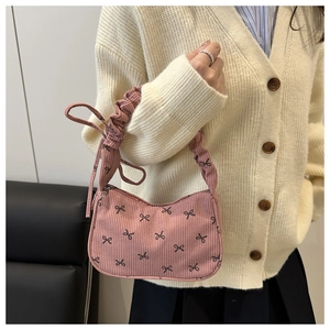 Detailed shot of pink corduroy shoulder bag with black bow print and pleated handle