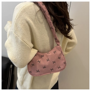 Detail of pink corduroy shoulder bag featuring black bow patterns and textured fabric