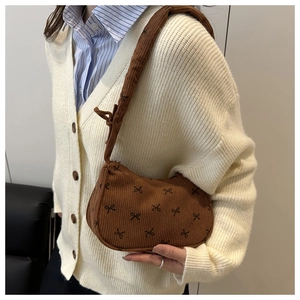 Close-up of brown corduroy crescent bag featuring small black bow tie pattern detail