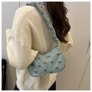 Detail of light blue corduroy shoulder bag with black bow prints and soft texture