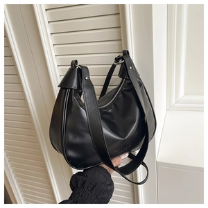 Detail of matte black crescent shoulder bag with silver zipper and smooth leather texture