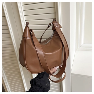 Detailed texture of brown crescent shoulder bag with metallic ring and wide strap